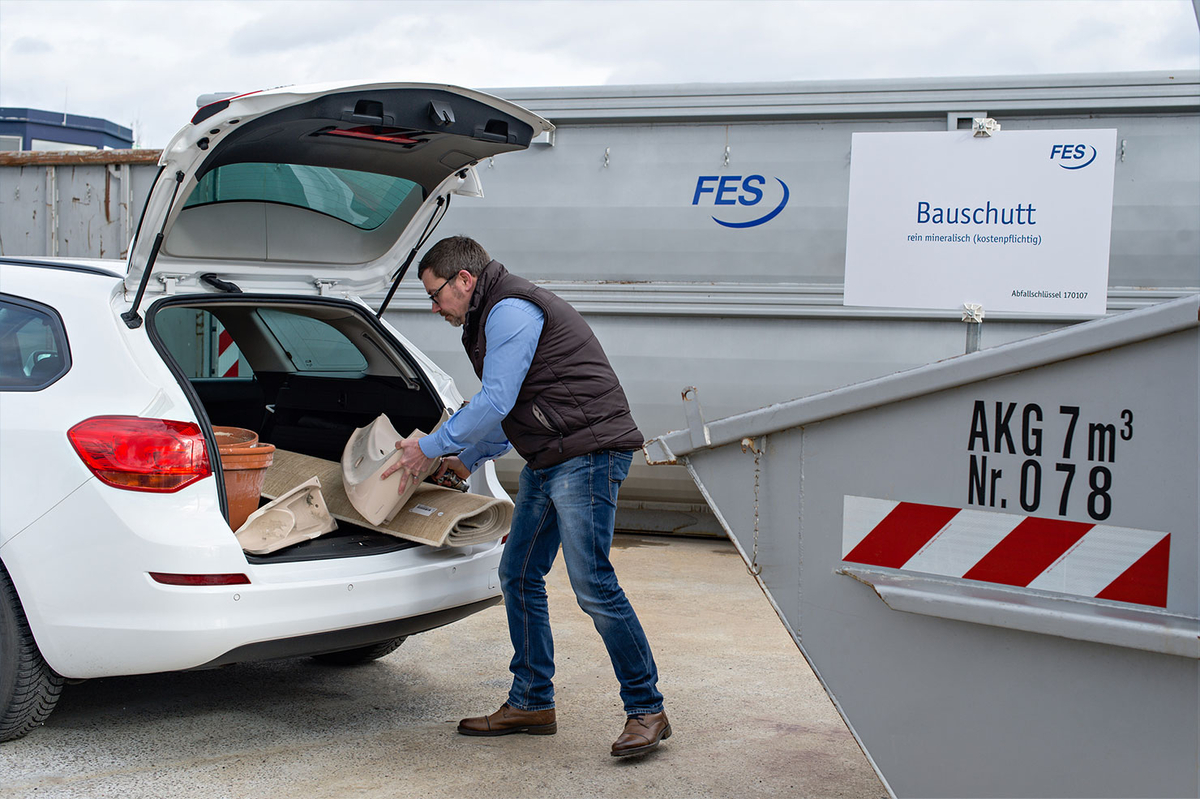 Mitarbeiter lädt Gegenstände aus Kofferraum